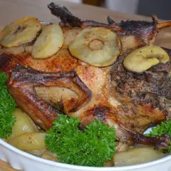Pieczona kaczka z jabłkami i tradycyjnym nadzieniem do kaczki, udekorowana natką pietruszki.