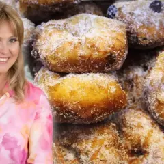 Uśmiechnięta Ewa Wachowicz prezentuje swoje pączki z ziemniakami, obficie posypane cukrem.