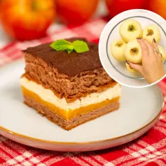 Pyszne ciasto Kilimandżaro z kremem i czekoladą, obok jabłka. W rogu widać rękę wybierającą jabłka do ciasta.