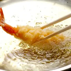 Krewetka w chrupiącej panierce panko smaży się w gorącym oleju.