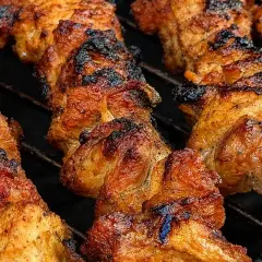 Szaszłyki z karkówki pieczone na grillu, apetycznie przypieczone, z widocznymi kawałkami mięsa na patykach.