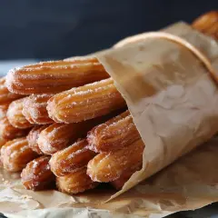 Pyszne, posypane cukrem churros, zawinięte w papier. Chcesz wiedzieć, churros co to? To smażone ciasto, idealne na deser!