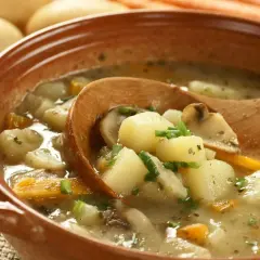 Zupa ziemniaczana przepis babci. Aromatyczna, domowa zupa z ziemniaków, marchewki i grzybów, podana w glinianej misce z drewnianą łyżką.