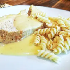 Kawałek pieczonego mięsa w kremowym sosie do potrawki, podany z makaronem fusilli.