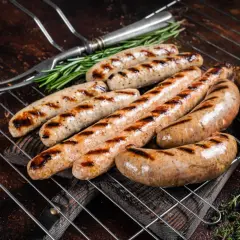 Aromatyczna biała kiełbasa z grilla, rumiana i soczysta, z ziołami i widelcem do serwowania.