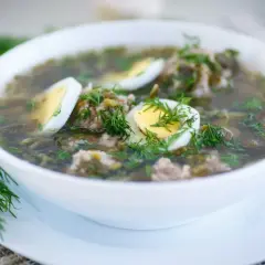 Zupa szczawiowa przepis babci: aromatyczna, zielona z dodatkiem mięsa i jajka, udekorowana świeżym koperkiem.