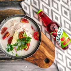 Aromaticzna, tradycyjna zupa tajska z kurczakiem, pomidorkami i limonką, obok butelka napoju wiśniowego.