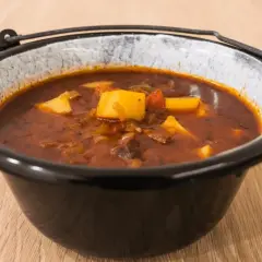 Gęsta, aromatyczna zupa gulaszowa przepis babci, z kawałkami mięsa i ziemniaków w głębokim, glinianym garnku.