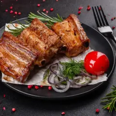 Soczyste żeberka z piekarnika, idealne na obiad. Podane z pomidorkiem, cebulą i rozmarynem.