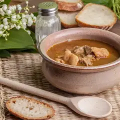 A rustic bowl brimming with the najlepsza zupa gulaszowa, accompanied by crusty bread slices and a wooden spoon.