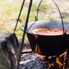 Tradycyjny kociołek przepis na ognisku. Gulasz gotuje się powoli nad ogniem, tworząc pyszne danie.