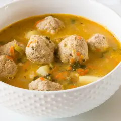 Zupa klopsowa babci: aromatyczny bulion z klopsikami, ziemniakami i warzywami. Smak dzieciństwa w miseczce.
