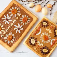 Wielkanocne mazurki ozdabiane bakaliami i orzechami, wyglądają jak kolorowe kwiaty na wiosennym tle.