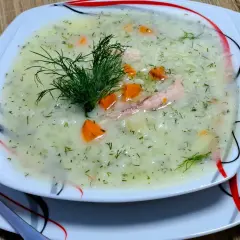 Aromatyczna zupa koperkowa z ryżem, kawałkami kurczaka i marchewką, udekorowana świeżym koperkiem.
