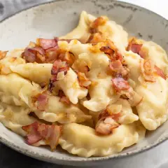 Pyszne pierogi ruskie z farszem Magdy Gessler, okraszone skwarkami i cebulką.