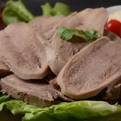 Pokrojone ozory wieprzowe ułożone na sałacie z pomidorkami i sosami.