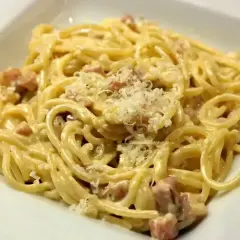 Pyszne spaghetti carbonara z kawałkami boczku i parmezanem. Idealna odpowiedź na pytanie: jaka śmietana do carbonary?