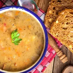 Aksamitna zupa grochowa, przepis babci, z kawałkami wędzonki i natką pietruszki, podana z chlebem żytnim.