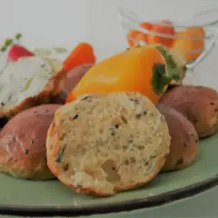 Babka jajowata co to jest? Puszyste bułeczki z ziołami i czarnuszką, jedna przekrojona, obok papryczki i ser.