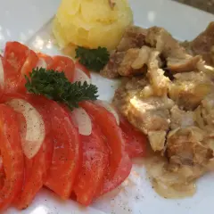 Świeżonka duszona z cebulką, podana z ziemniakami i sałatką z pomidorów i cebuli.