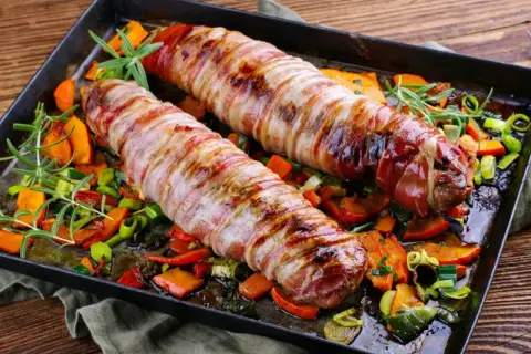 Pieczone polędwiczki wieprzowe w boczku, podane z pieczonymi warzywami i rozmarynem. Pyszna okrasa na obiad.