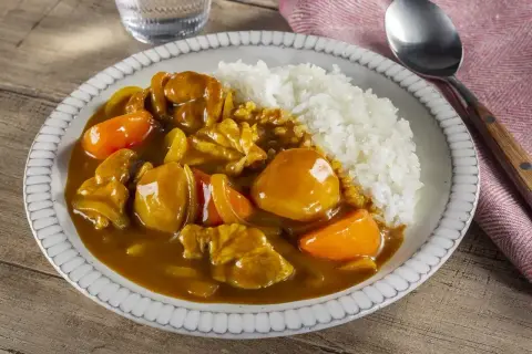 Pyszne danie z ryżem i kurczakiem w aromatycznym sosie przyprawy curry, z kawałkami marchewki.