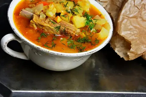 Gęsta, aromatyczna zupa na żeberkach z ziemniakami i marchewką, posypana świeżym koperkiem.