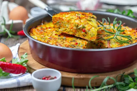 Pyszna, warzywna zapiekanka z jajek i warzyw, idealna na lekka kolacja. Podana z gałązką rozmarynu i papryczką chili.