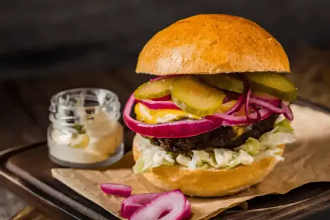 Pyszny hamburger z soczystą wołowiną, chrupiącą sałatą, piklami, czerwoną cebulą i majonezem. Idealny przepis na to, jak zrobić hamburgera.