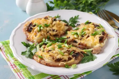Schab w plastrach pieczony w piekarniku z pieczarkami i serem, posypany szczypiorkiem.