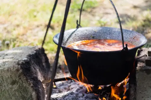 Tradycyjny kociołek przepis na ognisku. Gulasz gotuje się powoli nad ogniem, tworząc pyszne danie.