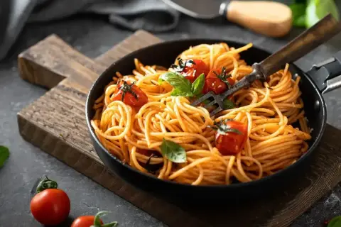 Pyszne spaghetti z pomidorkami i bazylią, idealne na smaczne obiady domowe przepisy. Widok z góry na talerz pełen makaronu.