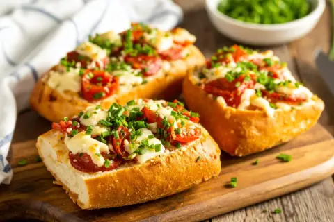 Pyszne zapiekanki z airfryer z serem, pomidorkami i szczypiorkiem na chrupiącej bagietce.