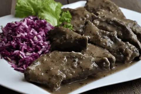 Pyszna wątróbka w sosie, podana z surówką z czerwonej kapusty i sałatą.
