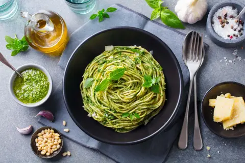 Pyszny obiad bez mięsa: spaghetti z pesto, świeżą bazylią, orzeszkami pinii i parmezanem.
