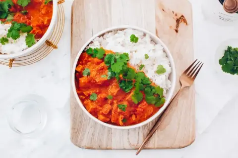 Pyszny kurczak w sosie curry z ryżem, udekorowany świeżą kolendrą. Prosty przepis na szybki obiad.