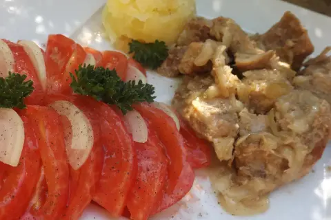 Świeżonka duszona z cebulką, podana z ziemniakami i sałatką z pomidorów i cebuli.