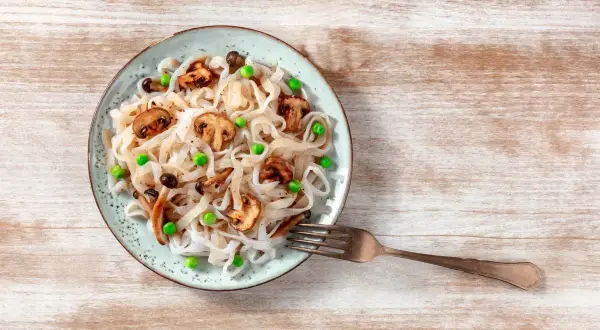 Talerz z makaronem konjac, pieczarkami i groszkiem. Inspiracja na zdrowe przepisy z makaronem konjac.