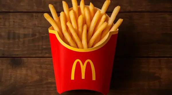Duże frytki McDonald's w czerwonym opakowaniu na drewnianym tle.