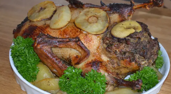 Pieczona kaczka z jabłkami i tradycyjnym nadzieniem do kaczki, udekorowana natką pietruszki.