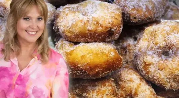 Uśmiechnięta Ewa Wachowicz prezentuje swoje pączki z ziemniakami, obficie posypane cukrem.
