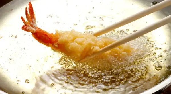 Krewetka w chrupiącej panierce panko smaży się w gorącym oleju.