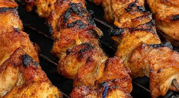 Szaszłyki z karkówki pieczone na grillu, apetycznie przypieczone, z widocznymi kawałkami mięsa na patykach.