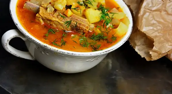 Gęsta, aromatyczna zupa na żeberkach z ziemniakami i marchewką, posypana świeżym koperkiem.