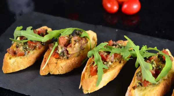 Cztery chrupiące bruschetty z pomidorami, ziołami i rukolą. Idealne tapas, co to jest? Pyszna przekąska!