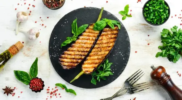 Grillowane bakłażany z bazylią i natką pietruszki. Idealne nietypowe dania z grilla, podane z czosnkiem, oliwą i pieprzem.