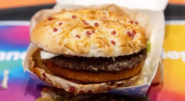Apetyczny burger drwala z chrupiącą bułką posypaną serem i kawałkami boczku, w środku soczysty kotlet i panierowany dodatek.