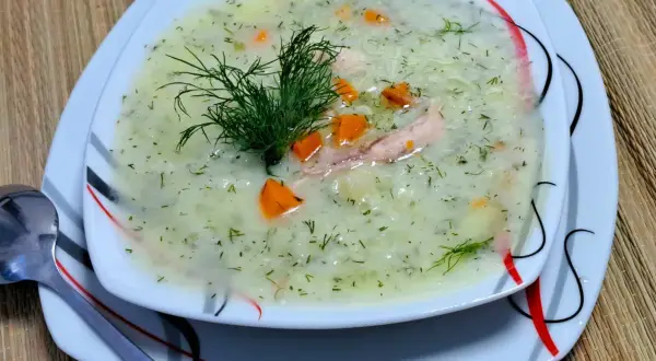 Aromatyczna zupa koperkowa z ryżem, kawałkami kurczaka i marchewką, udekorowana świeżym koperkiem.
