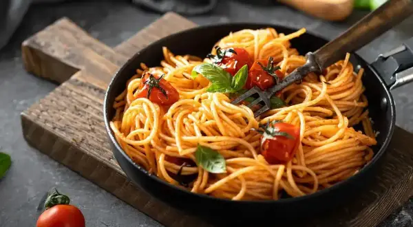 Pyszne spaghetti z pomidorkami i bazylią, idealne na smaczne obiady domowe przepisy. Widok z góry na talerz pełen makaronu.