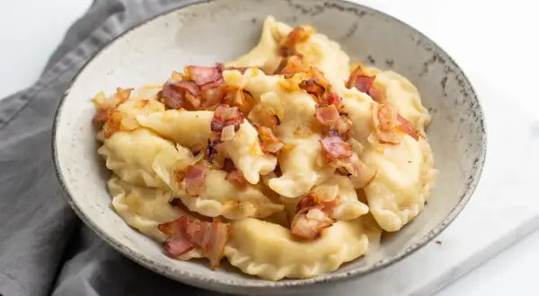Pyszne pierogi ruskie z farszem Magdy Gessler, okraszone skwarkami i cebulką.